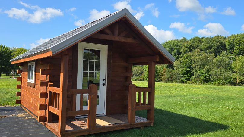 Small one room custom built cabin in the lush, green field.