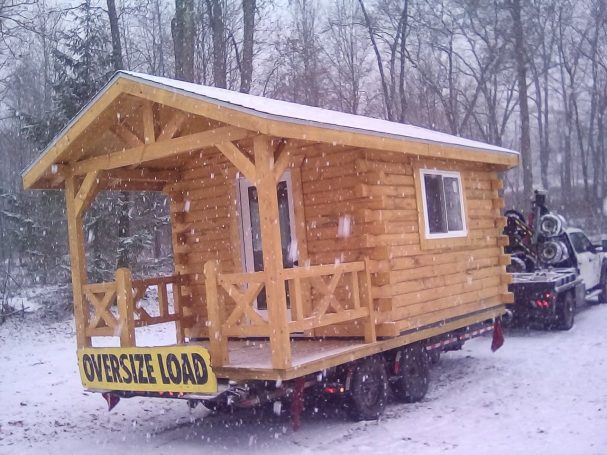 Hauling a miniature cabin with truck in the snowfall.