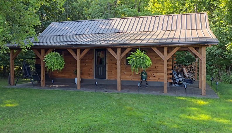 Long front porch with hanging plants on our custom built cabin.