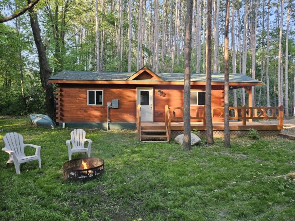 Front view of cabin with fire pit outside.